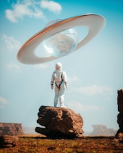 a man in a space suit standing on top of a rock