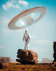 a man in a space suit standing on top of a rock