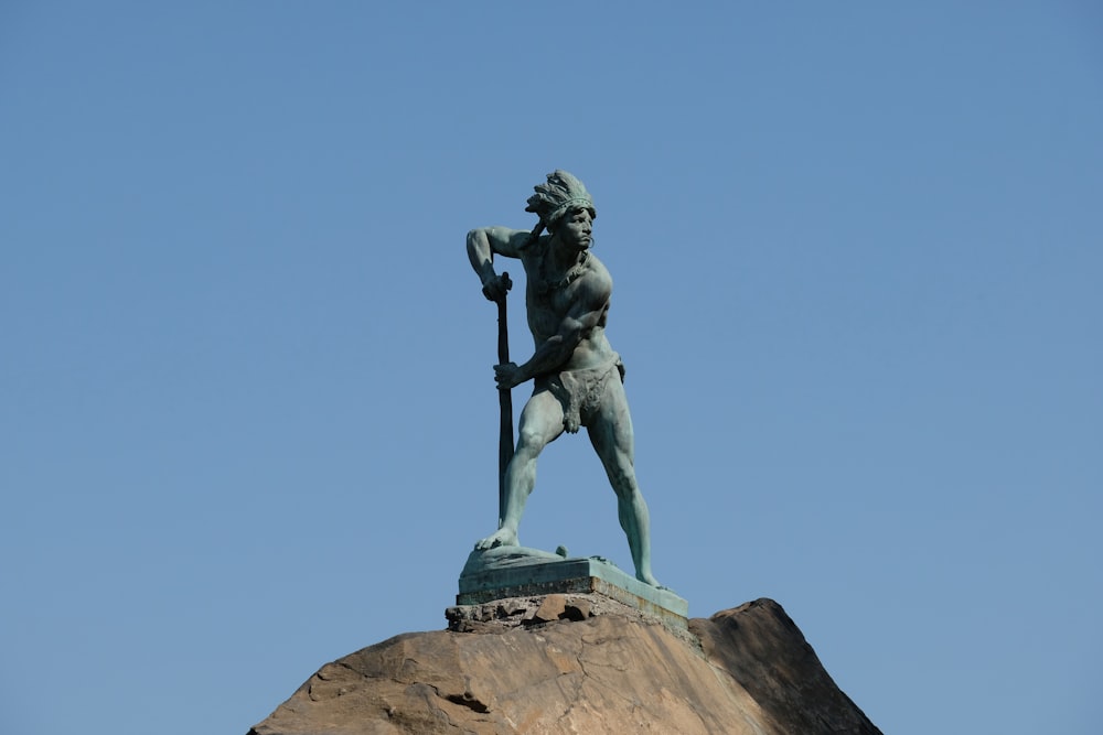 a statue of a man holding a spear on top of a hill