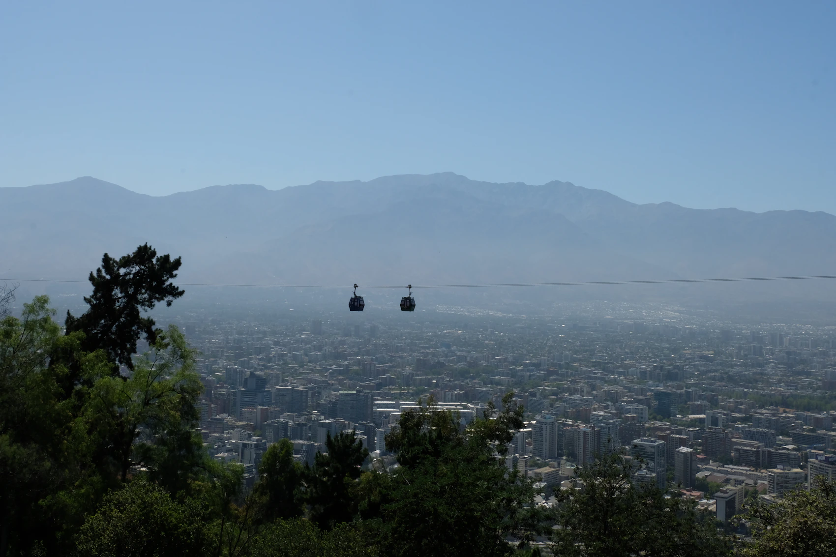 A cable car crossing above Santiago with the Andes behind