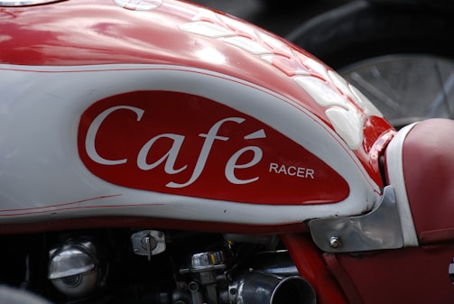Close-up of a shiny red motorcycle tank with black and white accents.