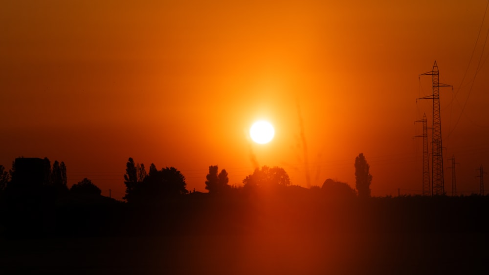 the sun is setting over a city with power lines