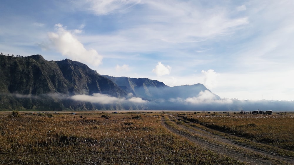 a dirt road in front of a mountain range