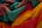 A close-up view of colorful, textured towels featuring vibrant shades of yellow, red, teal, and maroon, intricately folded and piled together.