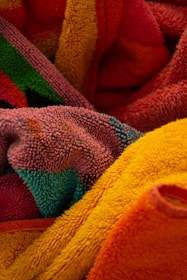 A collection of colorful, textured towels are intertwined, showcasing various bright colors and intricate patterns.