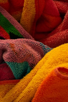 A collection of colorful, textured towels are intertwined, showcasing various bright colors and intricate patterns.