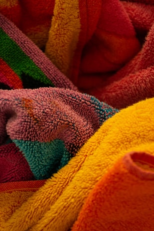 A collection of colorful, textured towels are intertwined, showcasing various bright colors and intricate patterns.