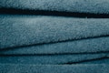 A close-up view of stacked, folded blue towels showing their soft, textured surface. The light catches the fibers, giving the fabric a slightly shiny look.