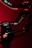 A close-up view of a black and red mechanical arm or stabilizer with a label RS3 PRO against a dark red background. The object is illuminated with red lighting, adding a dramatic effect.