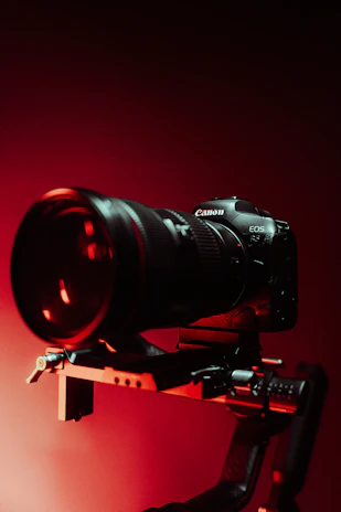 A sleek modern film camera setup in a dimly lit studio with red accent lighting.