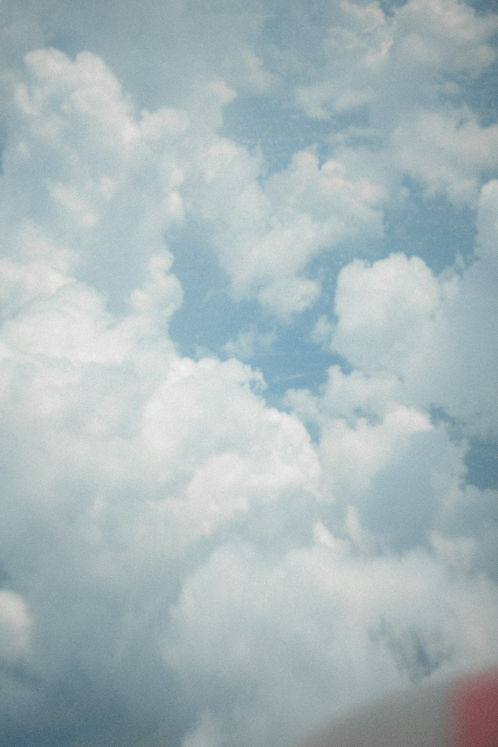 a plane flying through a cloudy blue sky