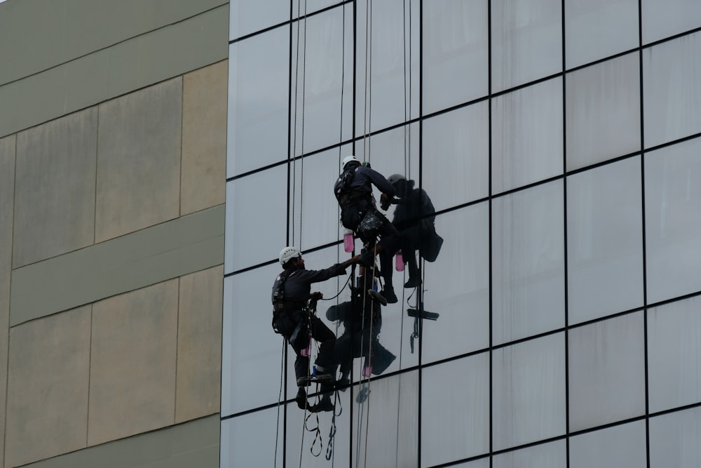 a group of people hanging from a high rise window