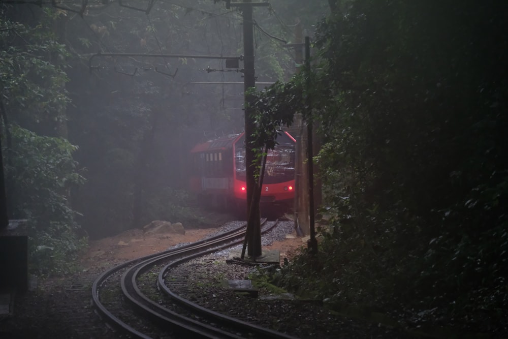 a red train traveling through a foggy forest