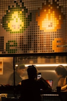 Pixelated avatars of Kobi Malul and Ofir Bahsan in their game studio workspace surrounded by vintage gaming gear.