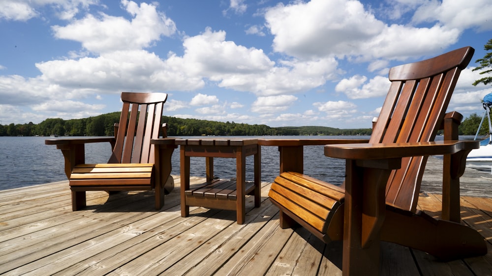 a couple of wooden chairs sitting on top of a wooden dock