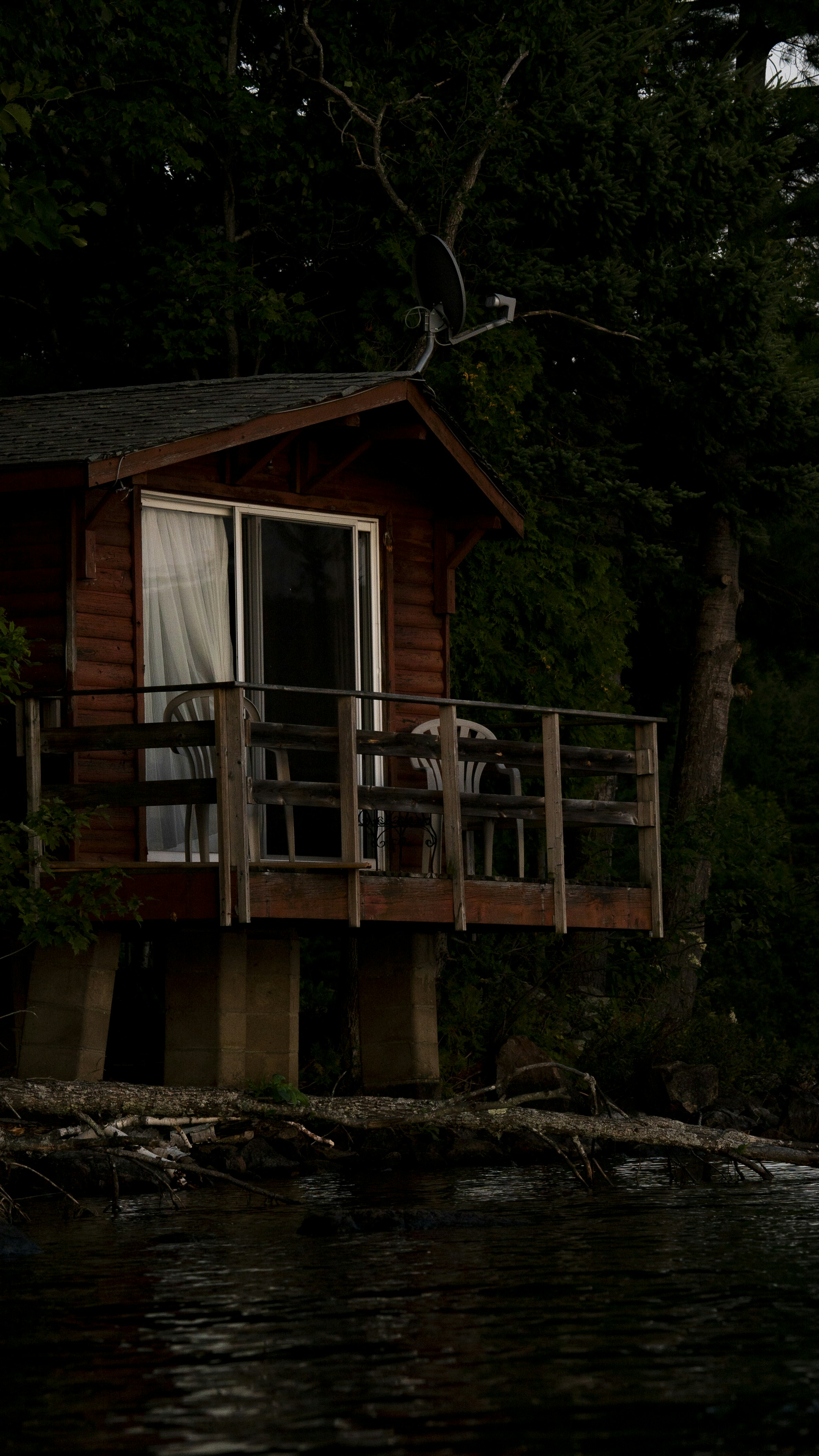 a cabin on the water with a porch and a deck