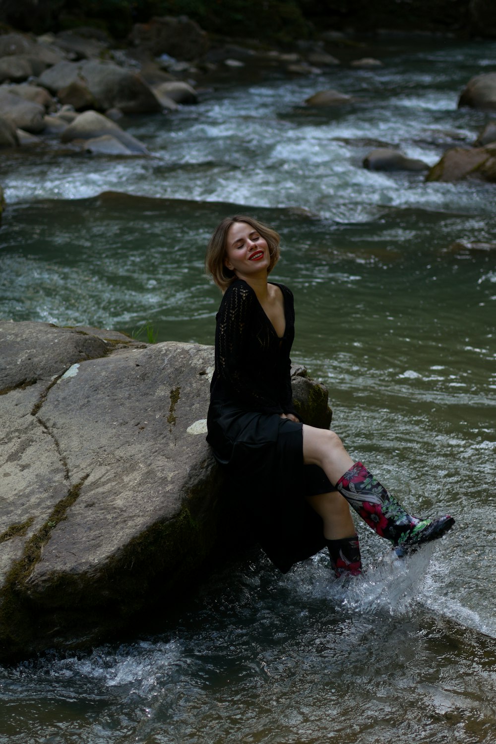 a woman sitting on a rock in a river