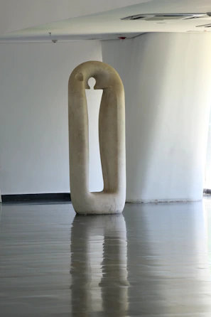A sleek modern sculpture displayed in a sunlit gallery space.