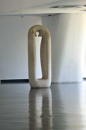 A sleek, minimalist sculpture displayed in a bright, airy gallery setting.
