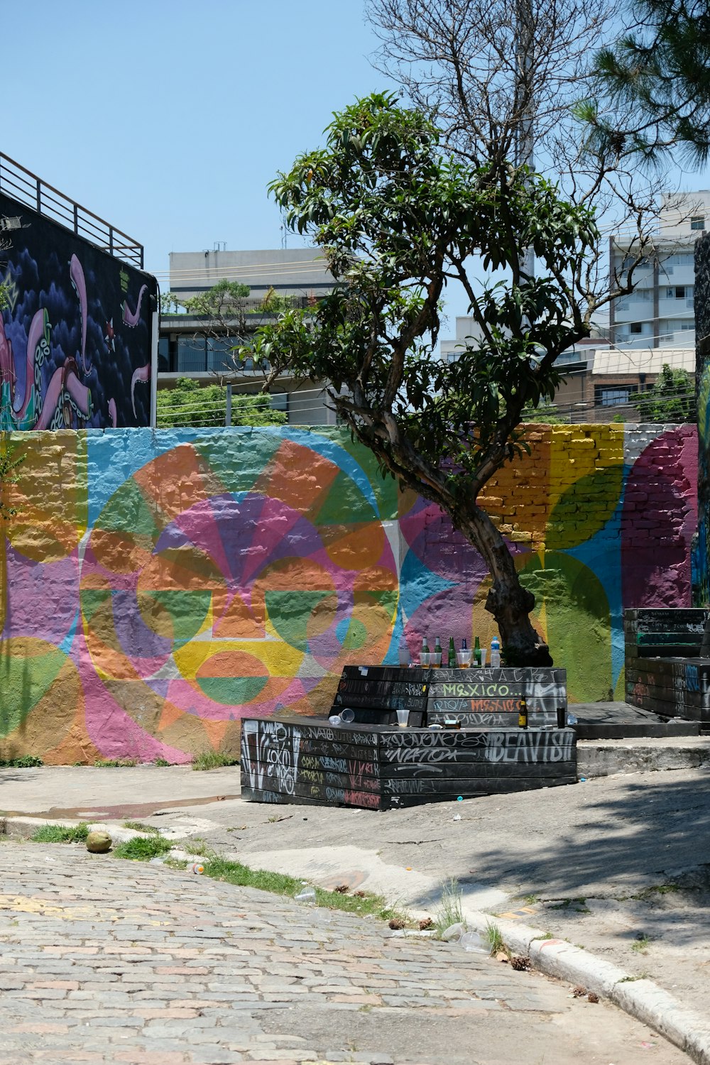 a colorful wall with a tree in front of it