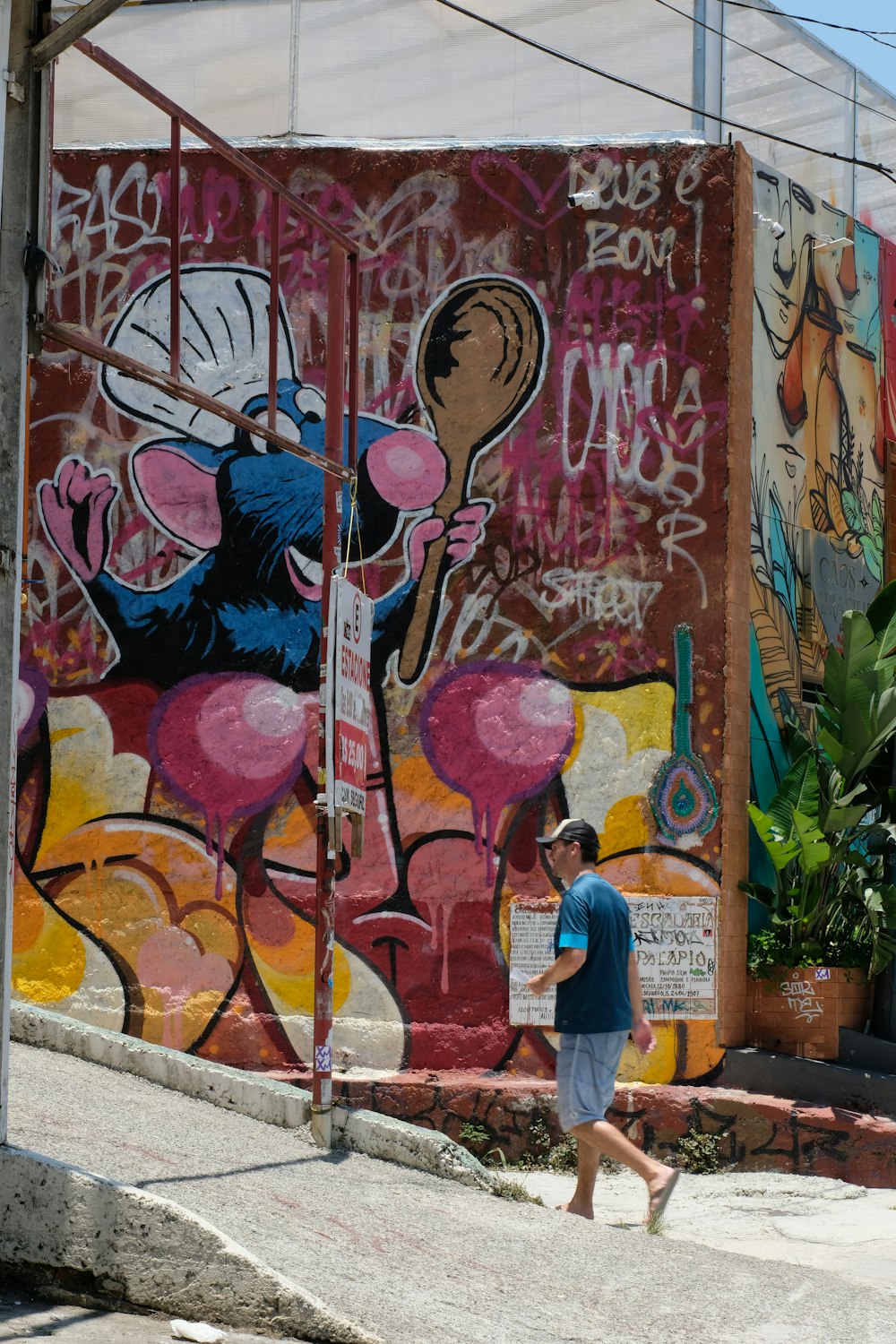 a man walking down a street past a wall covered in graffiti