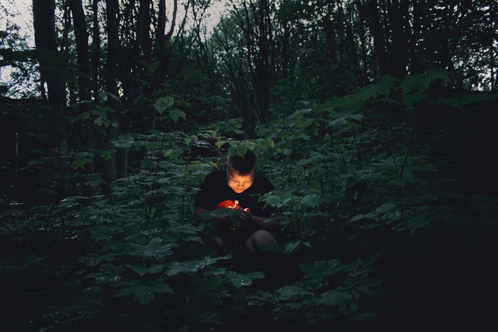 a person sitting in the woods with a flashlight