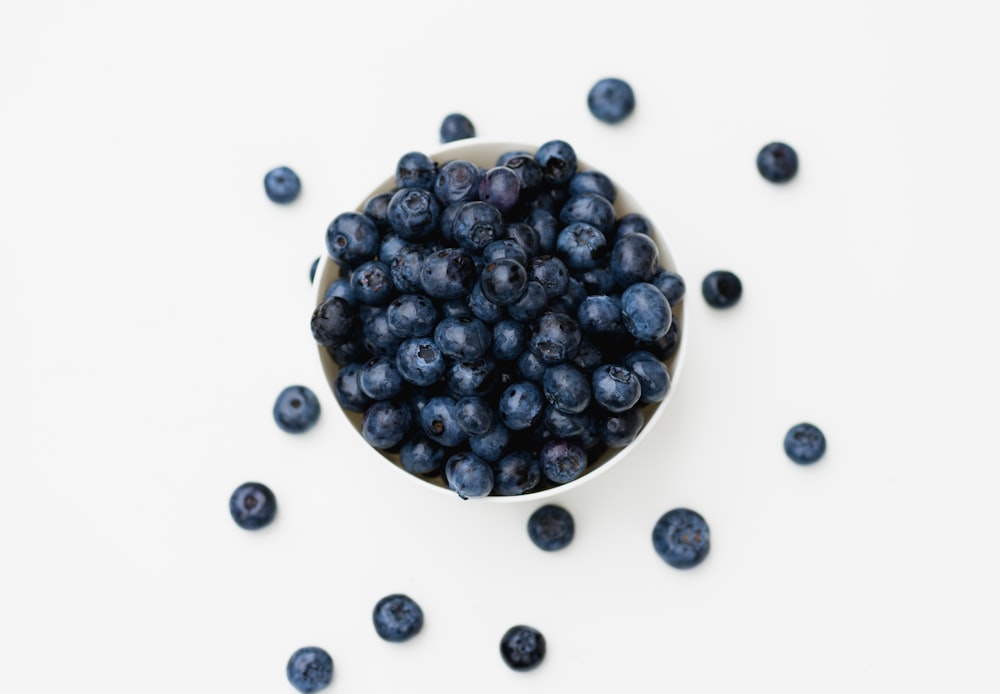 a white bowl filled with blueberries on top of a table