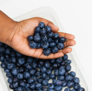 A hand holding a handful of colorful, fresh berries rich in antioxidants.