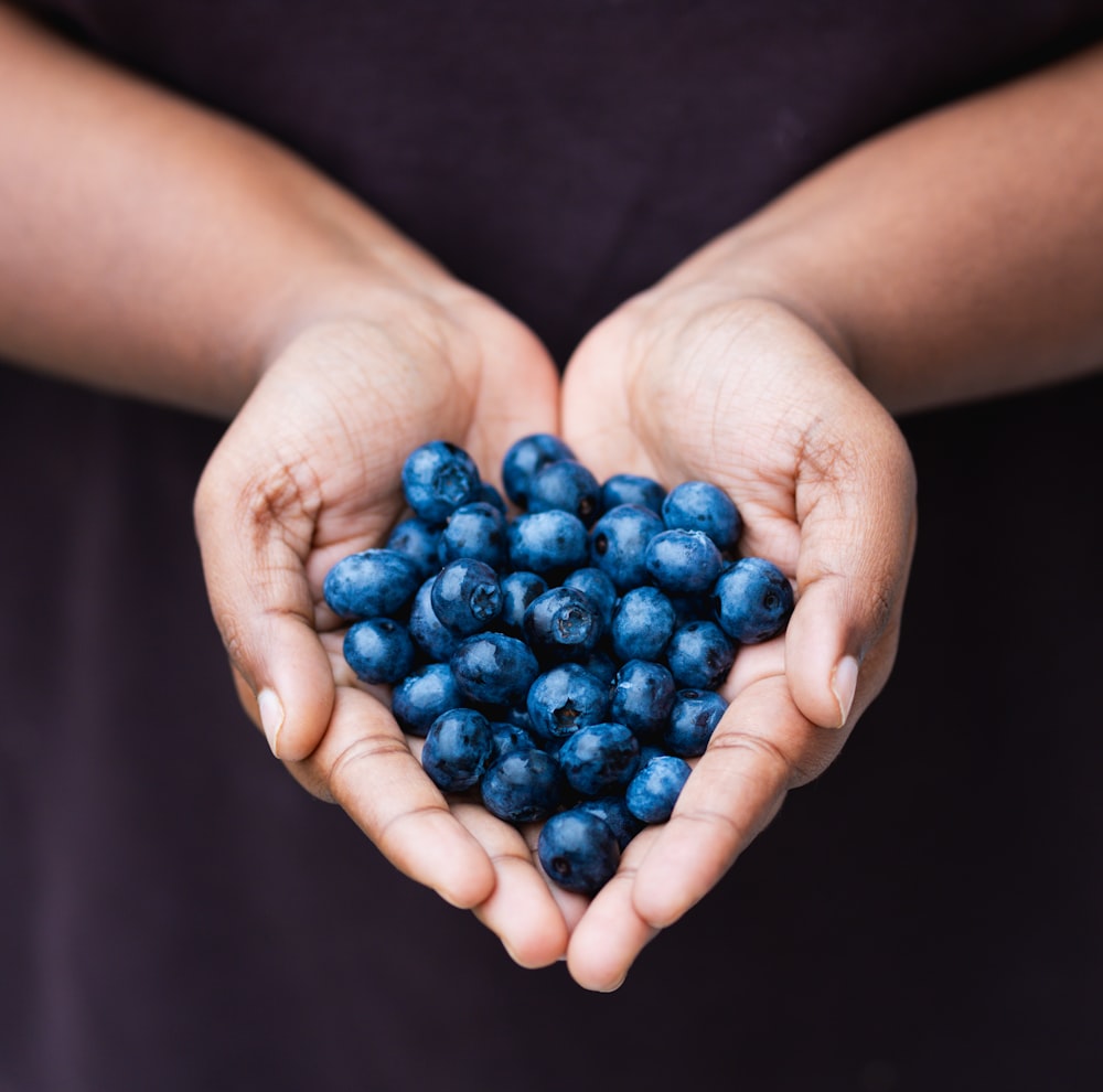 a person holding a handful of blueberries in their hands