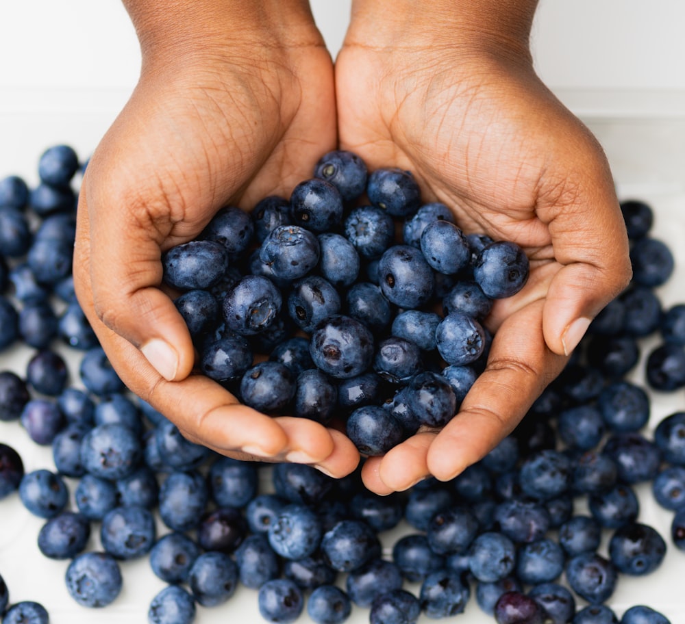 a person holding a handful of blueberries in their hands