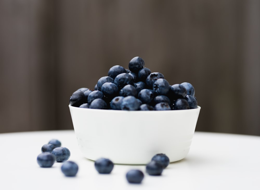 a white bowl filled with blueberries on top of a table