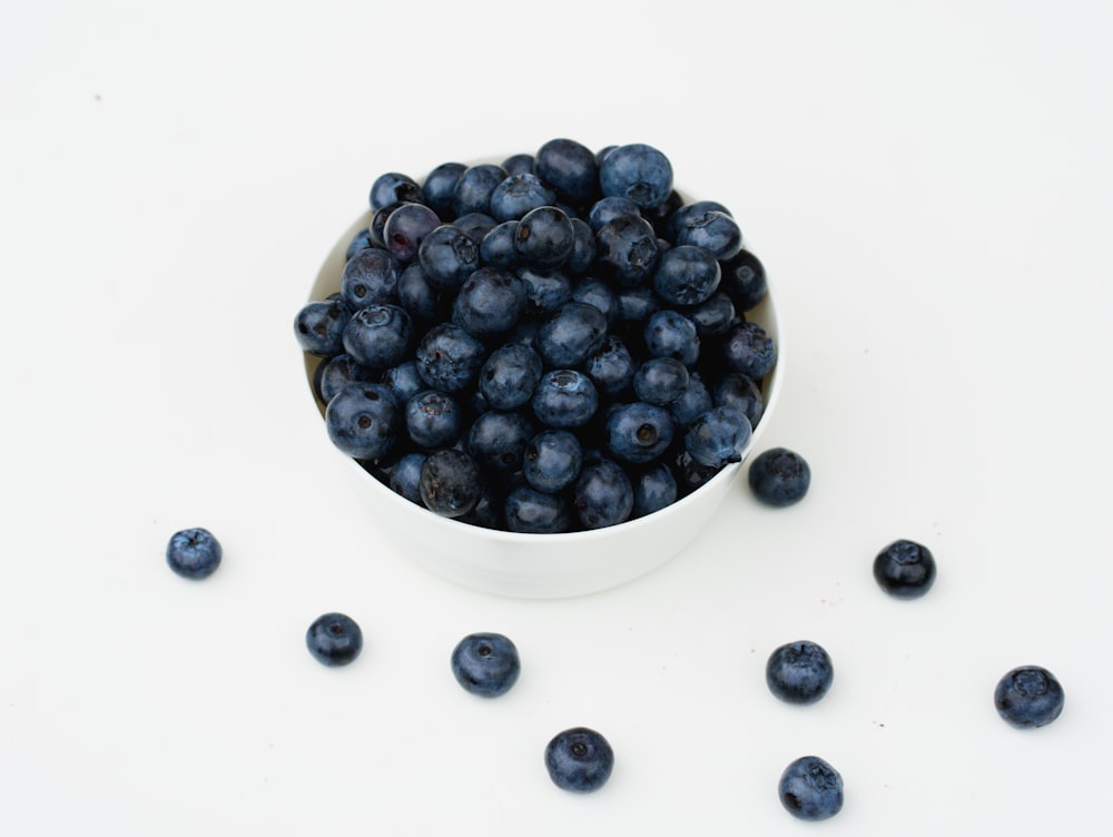 a white bowl filled with blueberries on top of a table