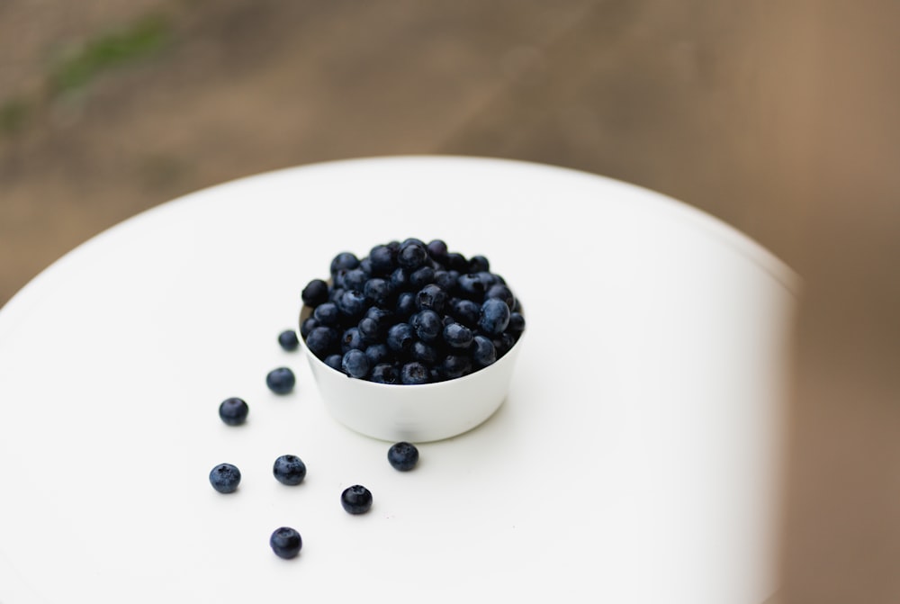 a white bowl filled with blueberries on top of a white table