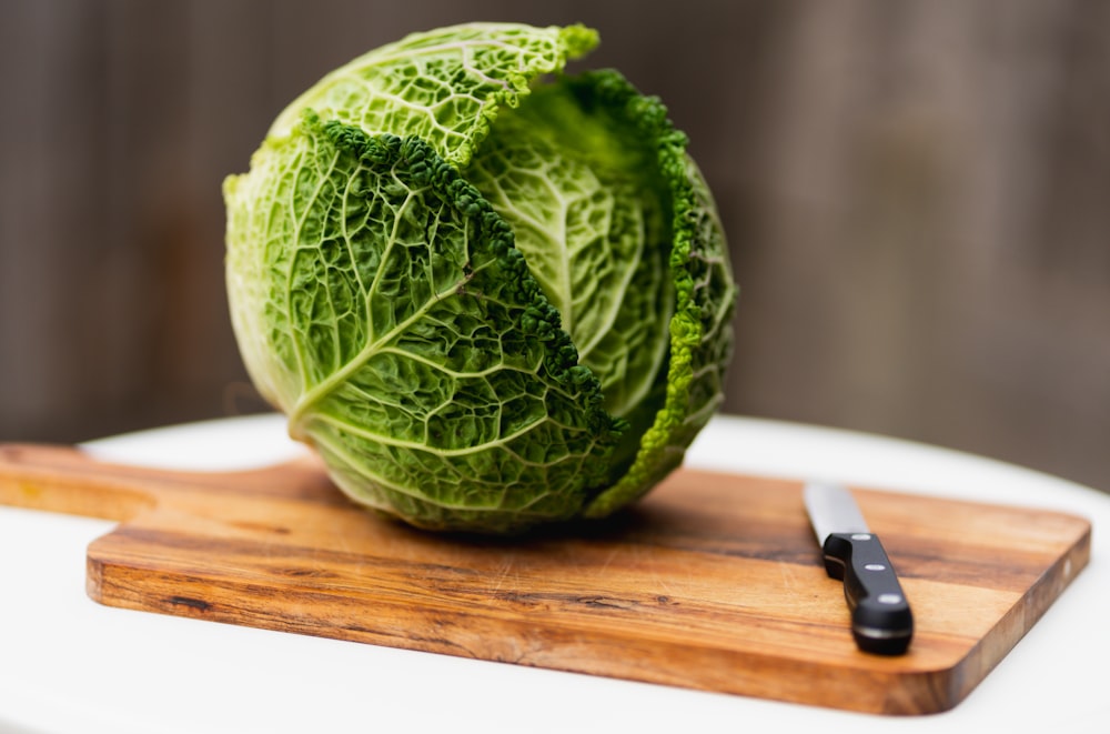 a head of cabbage on a cutting board with a knife