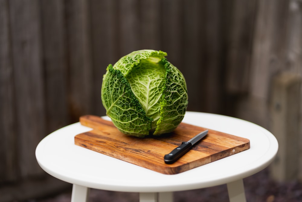 a head of cabbage sitting on top of a wooden cutting board