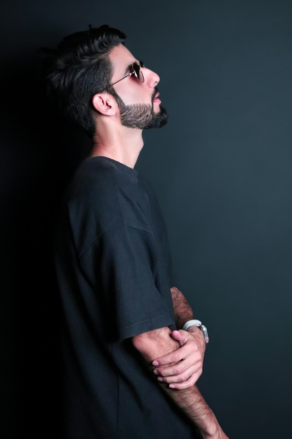 a man with a beard and glasses standing in a dark room