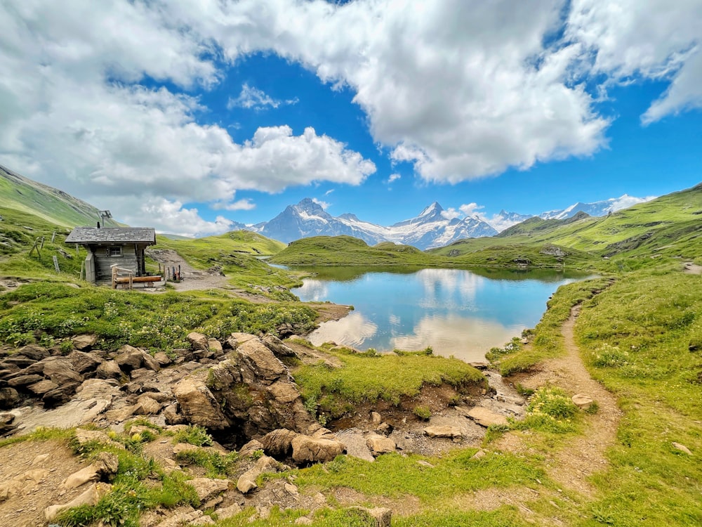 a small cabin sits on the side of a mountain lake