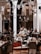 A cozy indoor setting with a group of musicians playing traditional instruments. The performers are dressed in cultural attire and are surrounded by an intimate audience seated at tables. Several ornate hanging lamps add a warm ambiance to the room, which features arches and wooden accents.