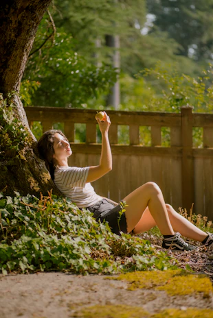 A peaceful moment showing someone enjoying a gummy outdoors in a sunlit garden.