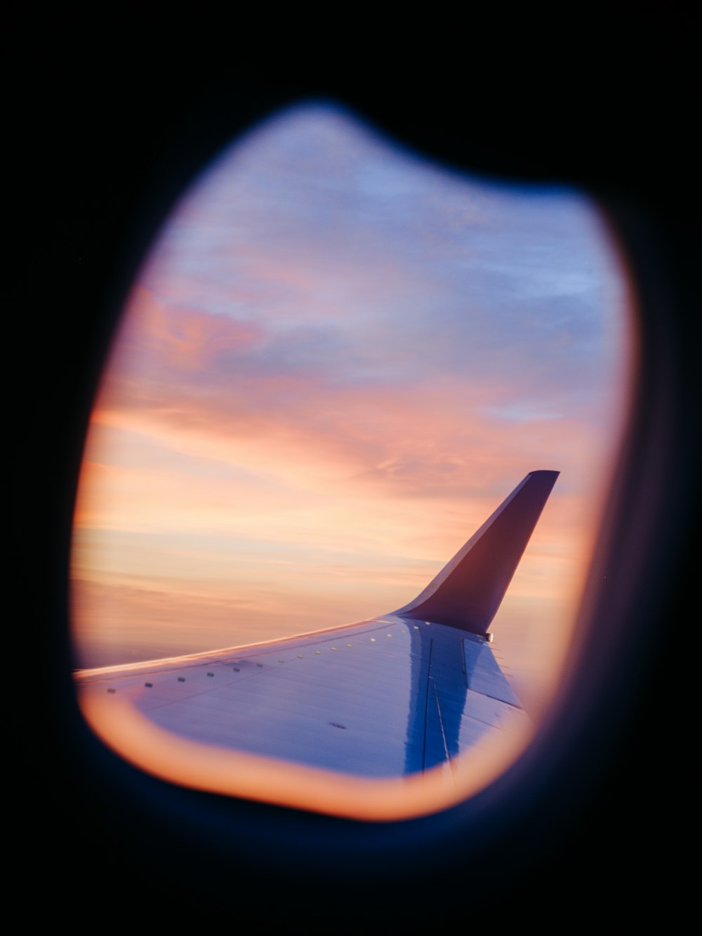 a view of the wing of an airplane at sunset