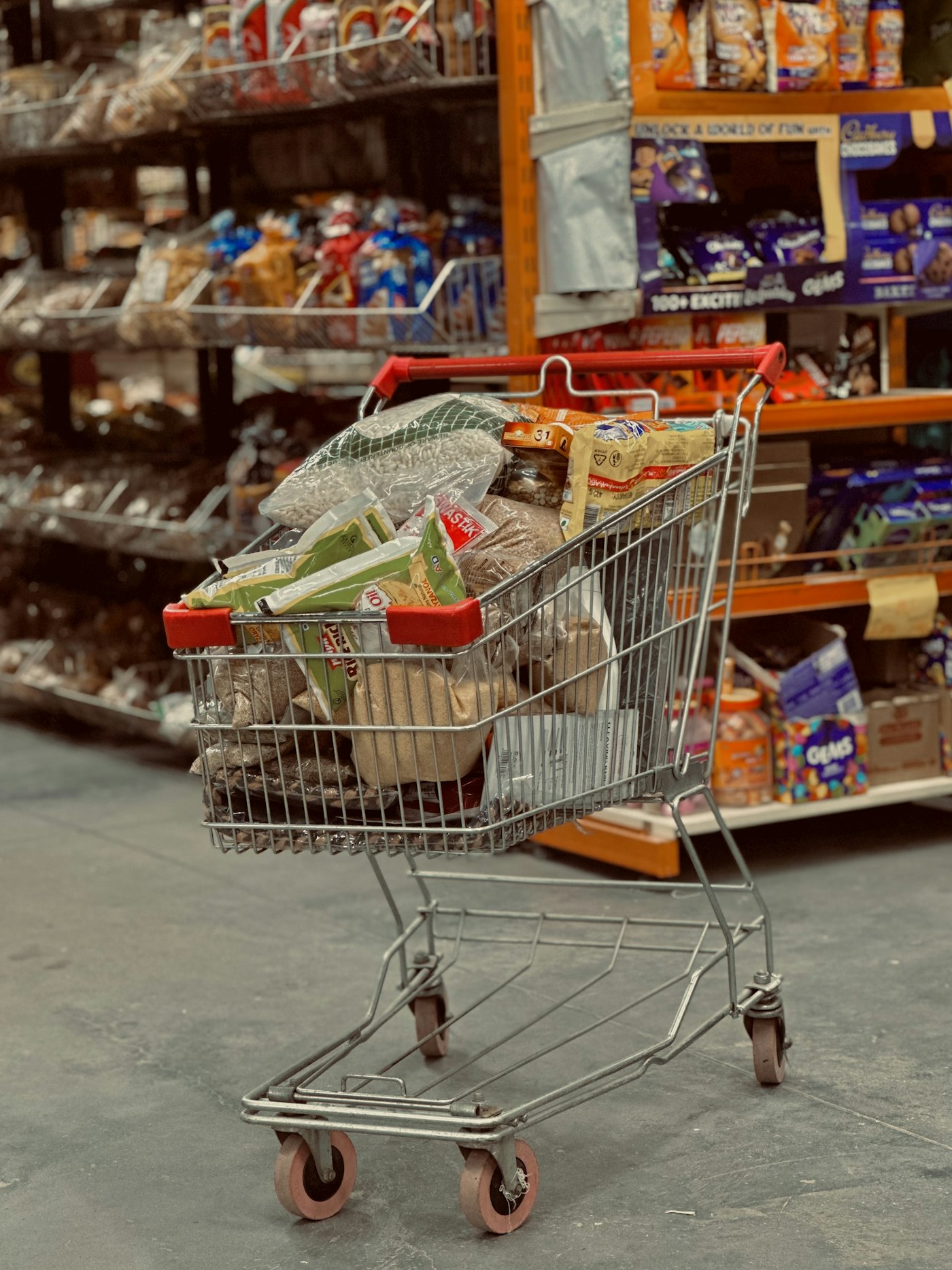 A loaded shopping trolley in a supermarket aisle
