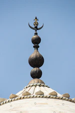 A technician polishing and replacing the crescent finial atop a mosque minaret.