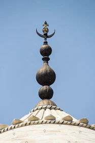 A technician polishing and replacing the crescent finial atop a mosque minaret.