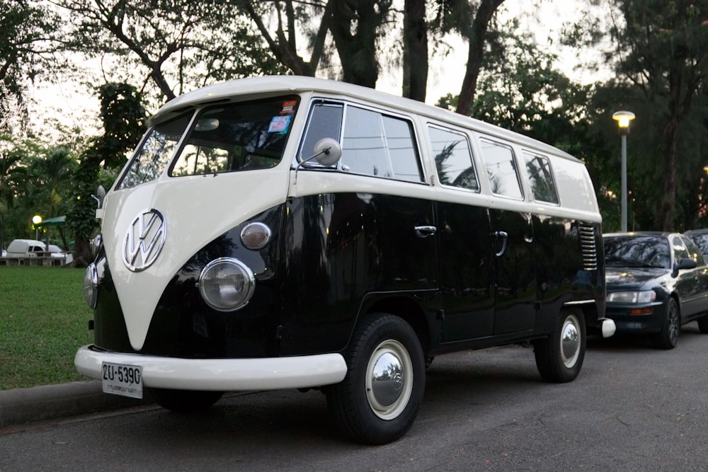 a black and white vw bus parked on the side of the road
