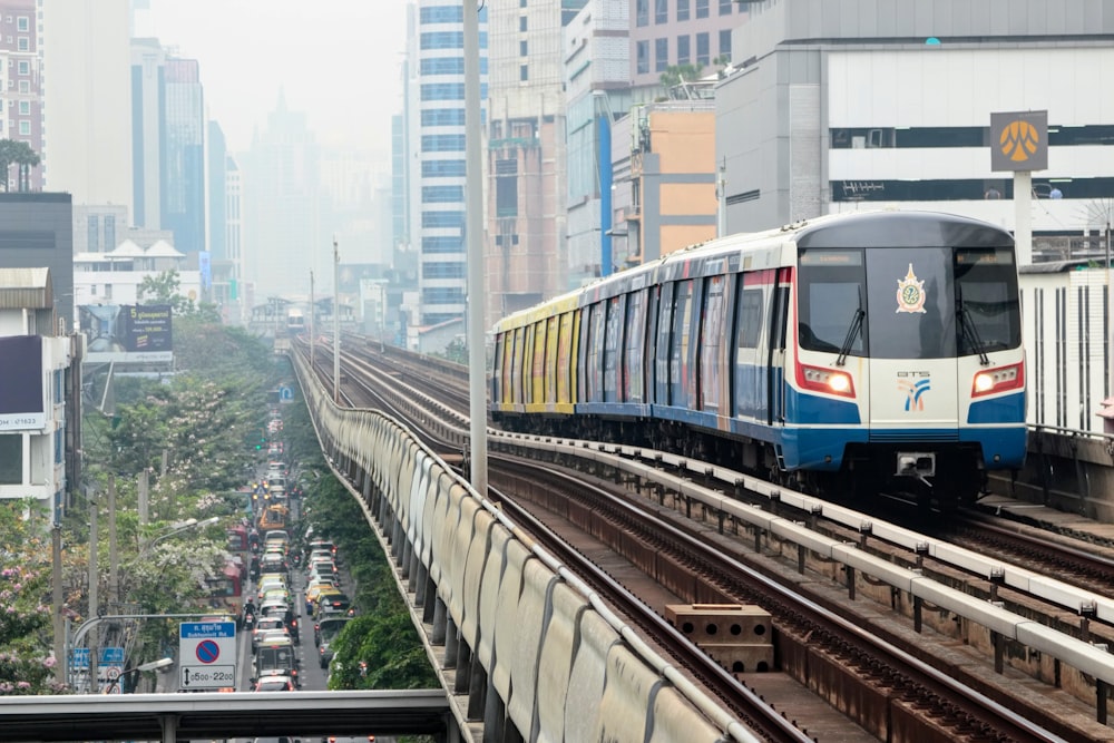 a train traveling down train tracks next to tall buildings