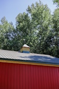 a red building with a metal roof and a clock tower