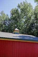 a red building with a metal roof and a clock tower