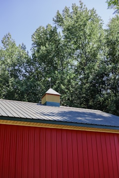 a red building with a metal roof and a clock tower