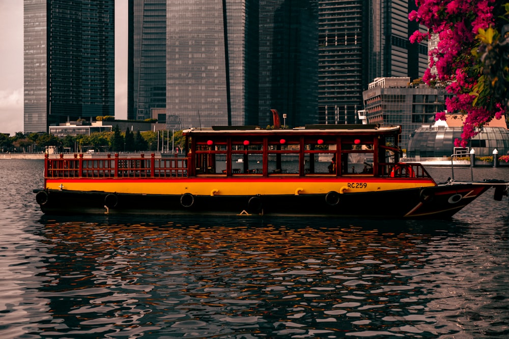 a yellow and red boat floating on top of a body of water