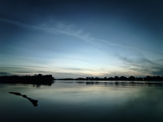 A quiet moment of reflection by a flowing river under a twilight sky.
